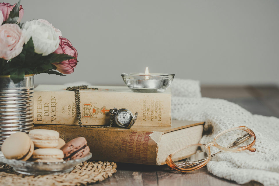 a collection of books, biscuits, flowers and a candle beside a blanket depicting bedtime