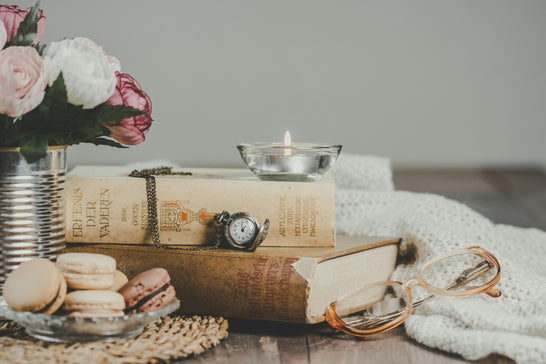 a collection of books, biscuits, flowers and a candle beside a blanket depicting bedtime